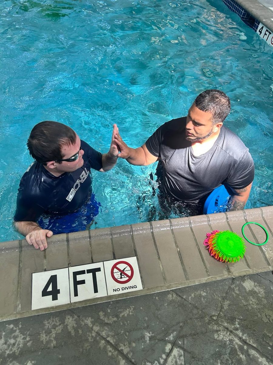 A swimmer and instructor sharing a high-five at the four-foot mark